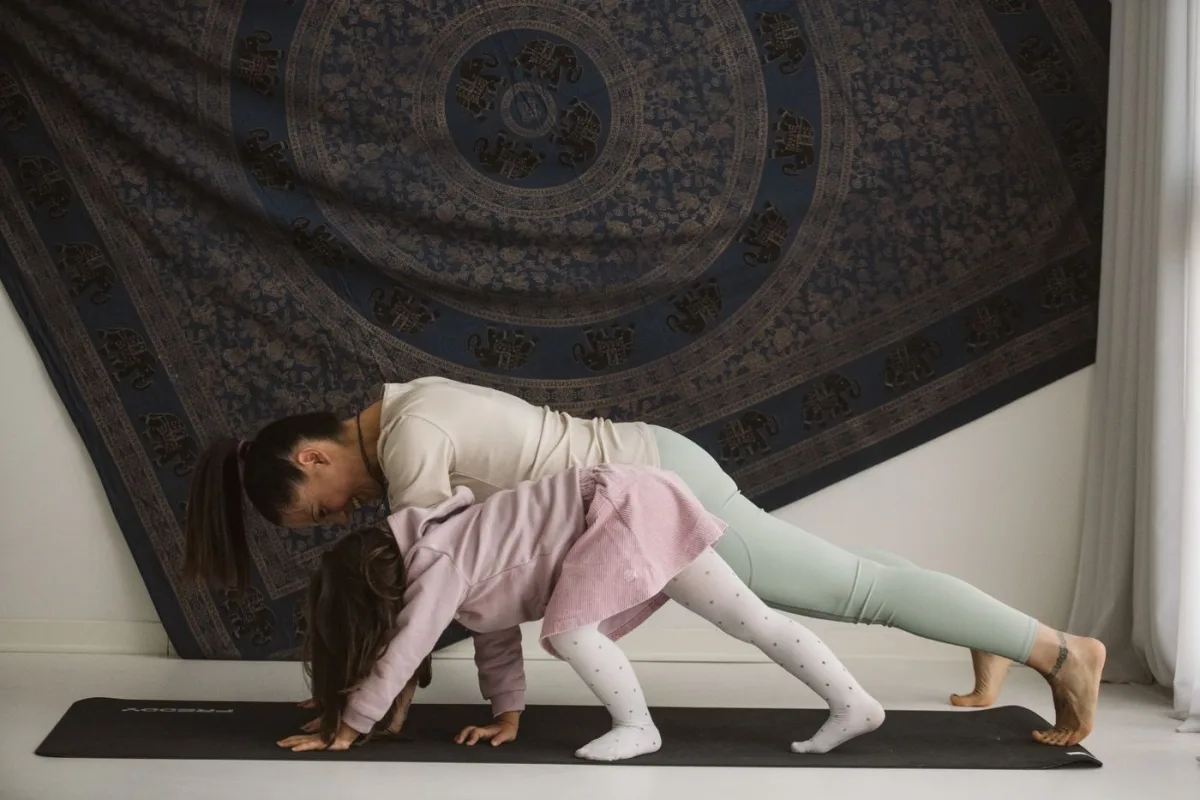Una mamma e una bambina praticano insieme una posizione yoga