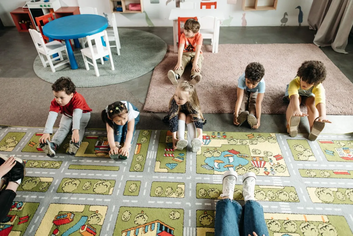 Bambini e bambine fanno un esercizio di allungamento in classe