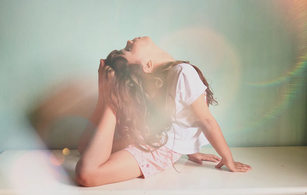 Una bambina prova una posizione di yoga in una stanza illuminata dal sole